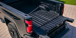 A Black Chevy Silverado LD Parked on a Driveway with Its Multi-Flex Tailgate Open Showing the Spacious Truck Bed.