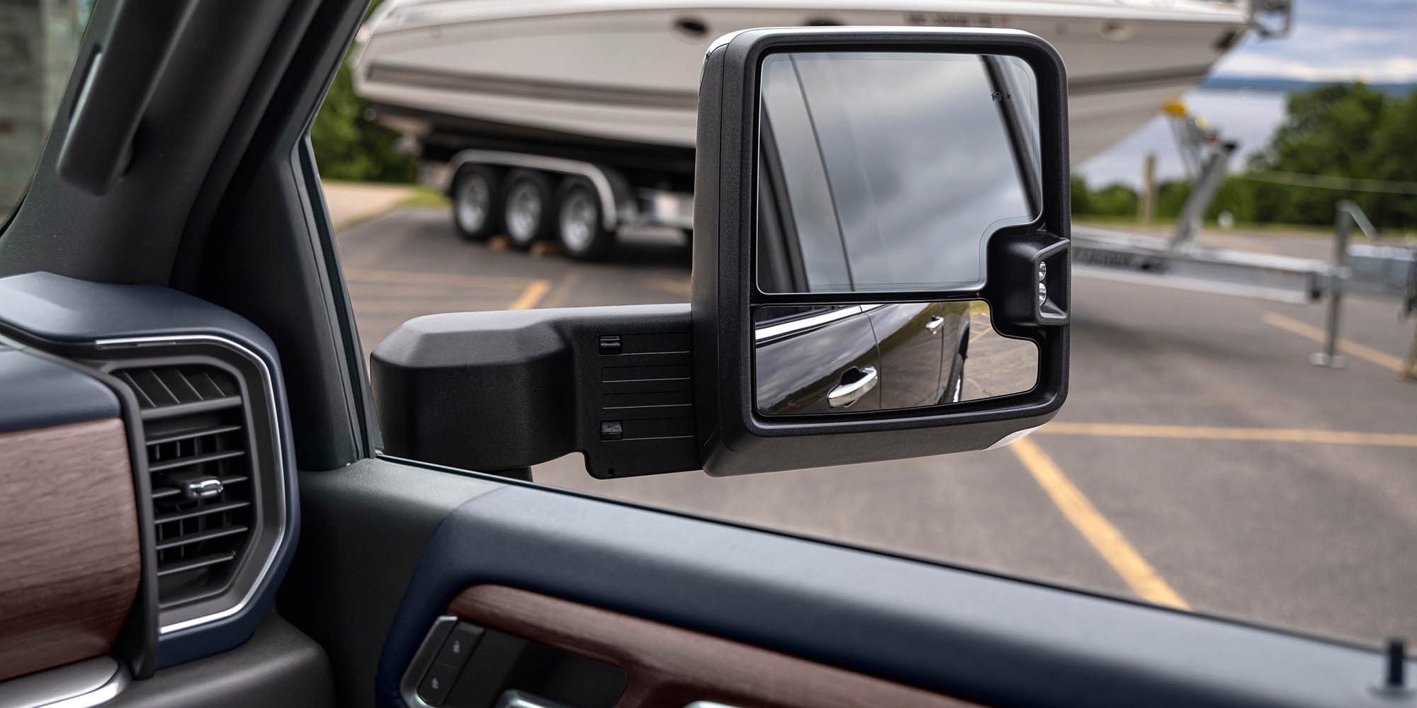 Towing mirror of a 2026 Chevrolet Silverado HD with a boat trailer in the background