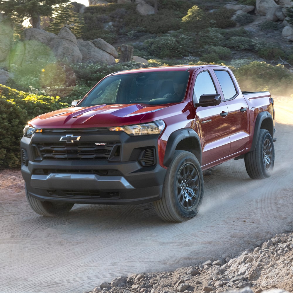 A Red Chevy Colorado Driving Along a Dusty Dirt Road.