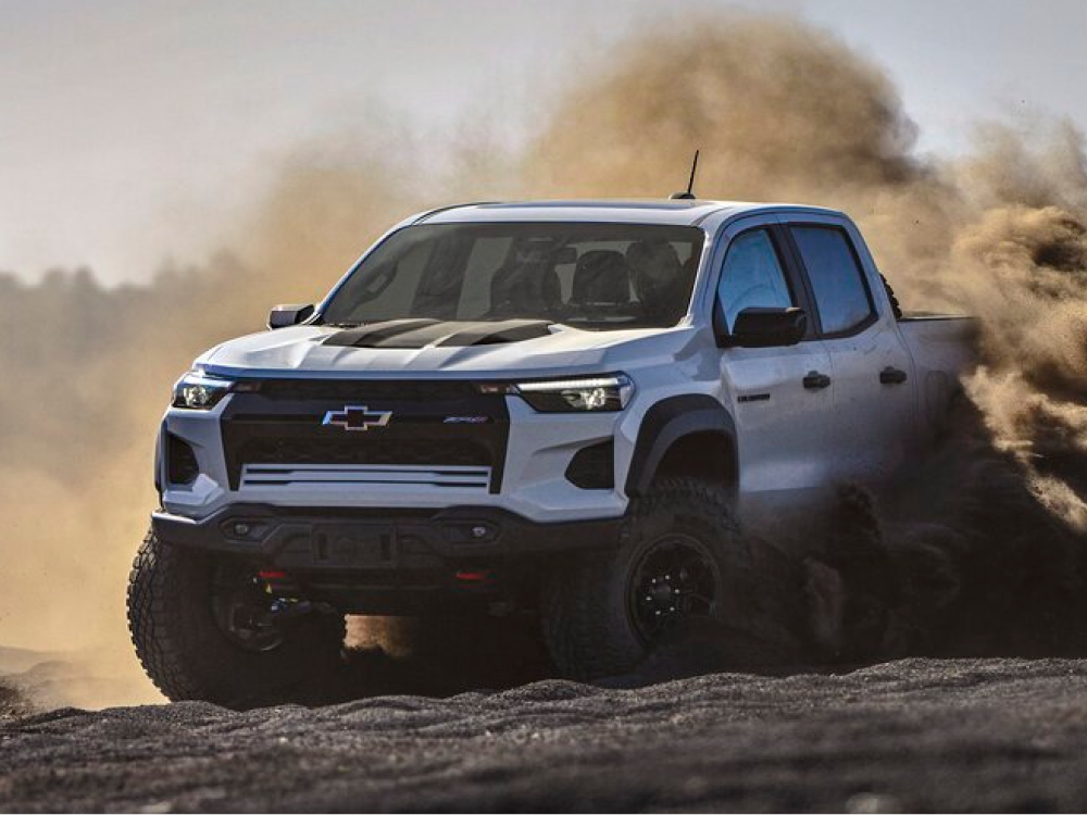 A Chevy Colorado Driving Through a Dusty Off-Road Trail With Dirt Flying Around the Vehicle.