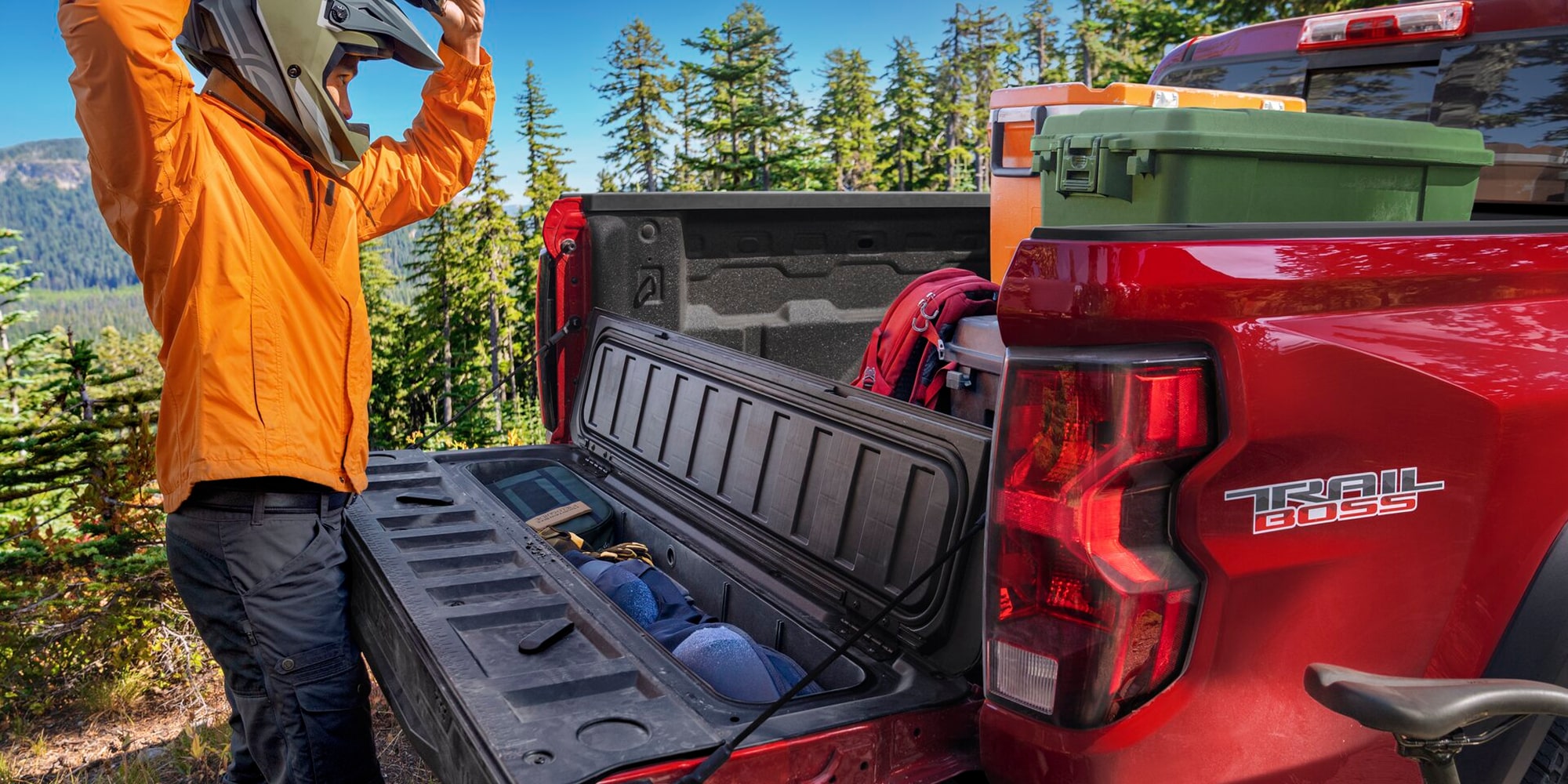 Bed of a Red Chevy Colorado Loaded With Outdoor Gear and Camping Equipment While Parked at a Campsite.