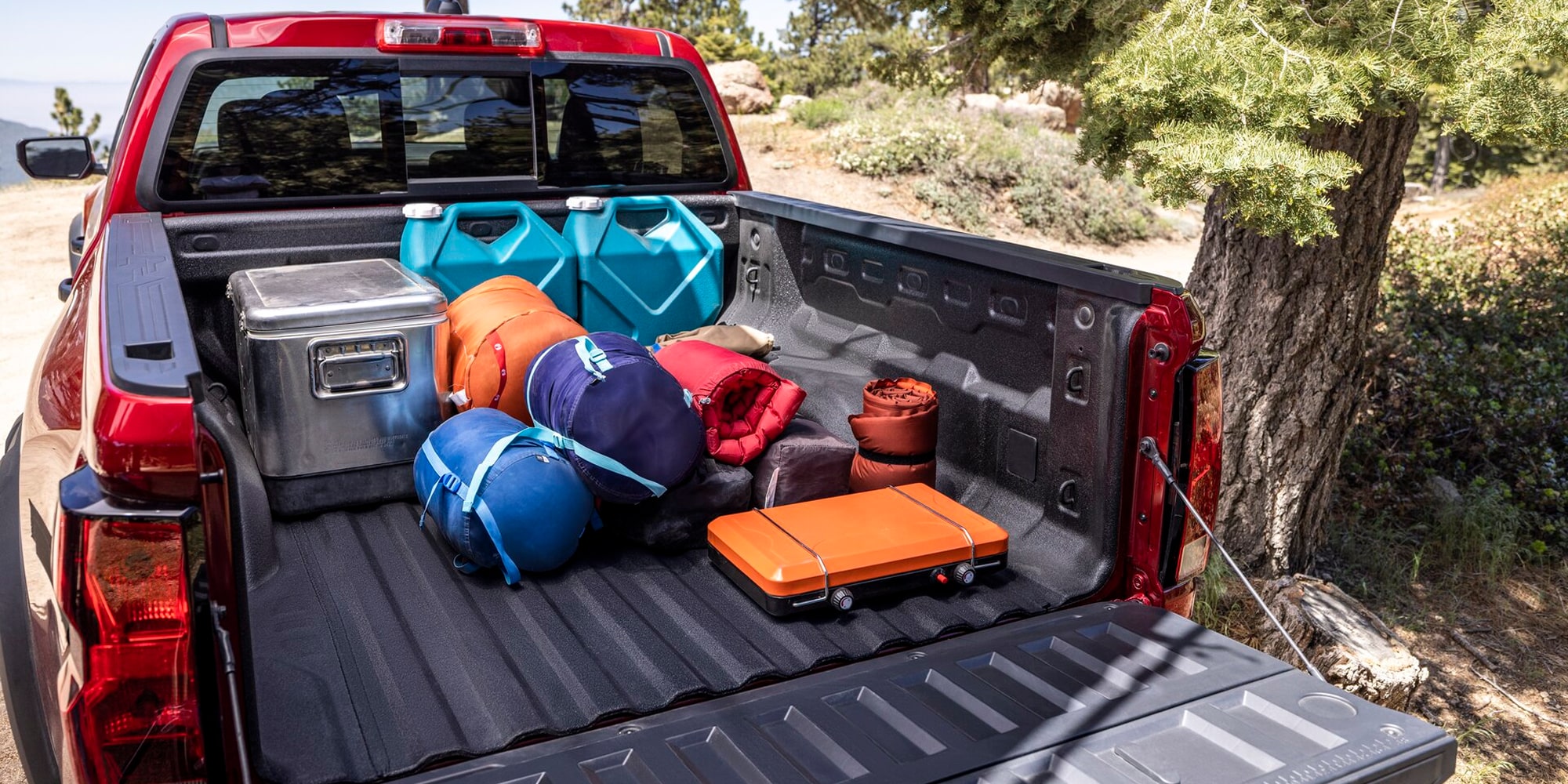 Bed of a Red Chevy Colorado Carrying Duffel Bags, Coolers, and Outdoor Gear During an Outdoor Adventure.