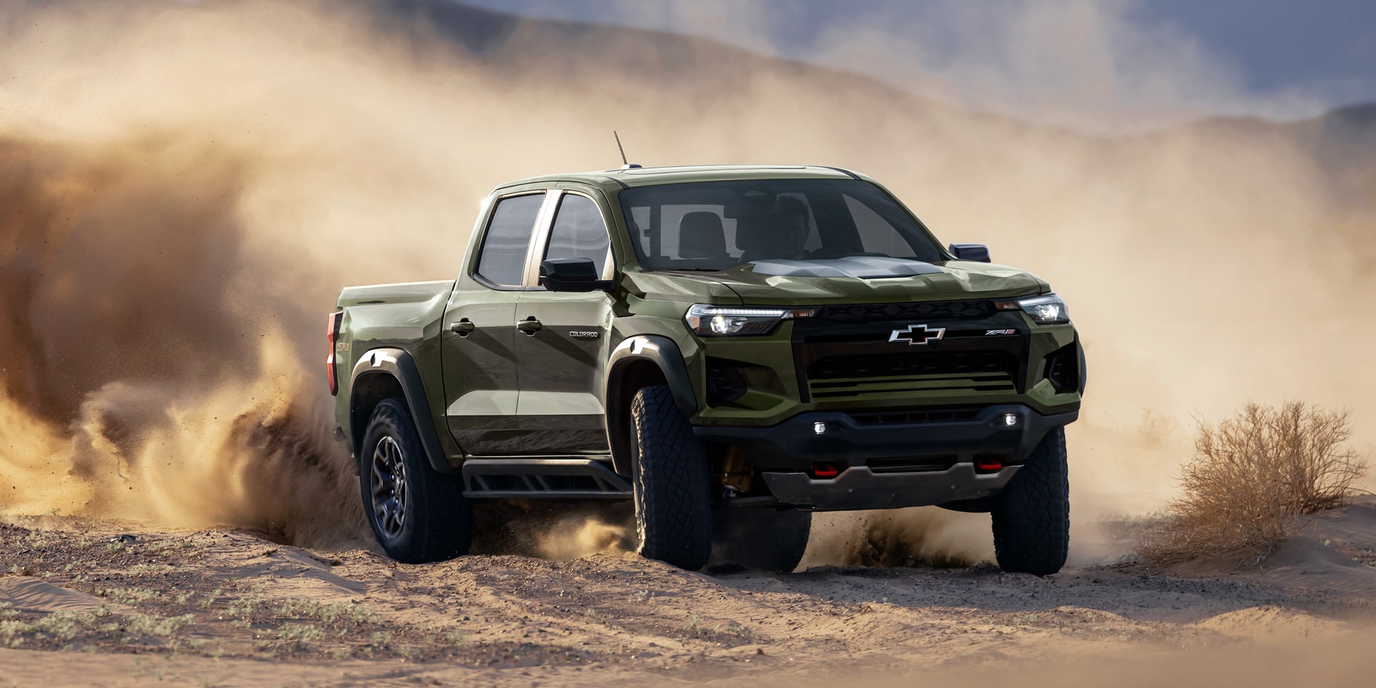 A Black Chevy Colorado Driving Through a Dusty Off-Road Trail With Dirt Kicking Up Behind the Truck.