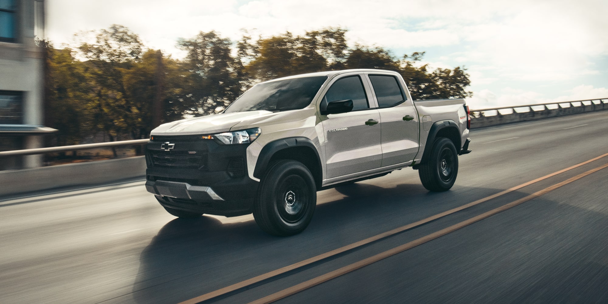 A Chevy Colorado Driving Along a Highway With a City Skyline Visible in the Background.