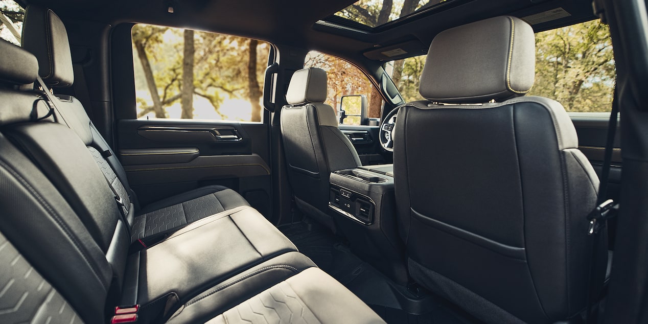 A Wide View of the Rear Passenger Area Inside a Chevy Silverado HD Featuring Spacious Leather Seating, Rear Climate Vents, and Generous Legroom Throughout the Cabin