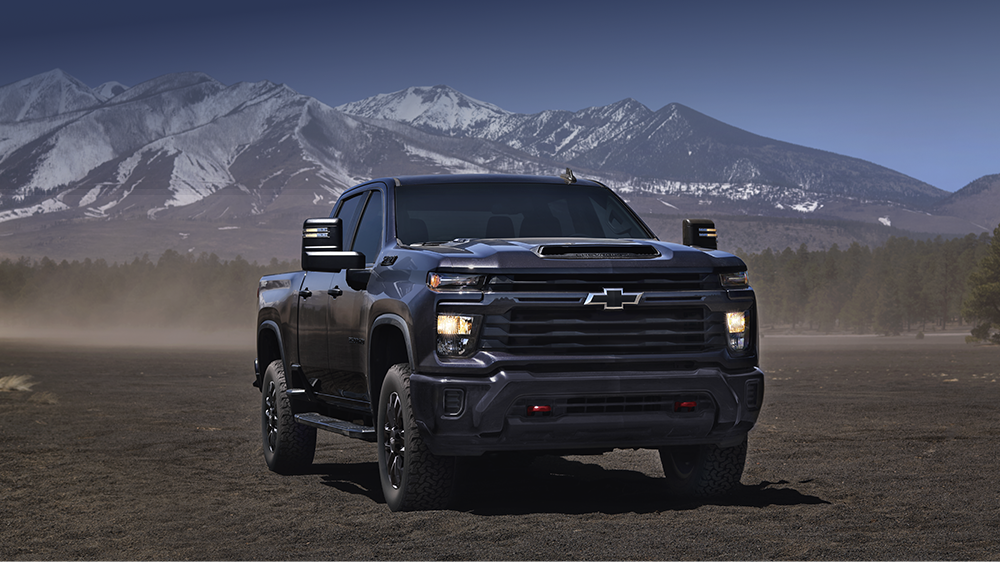 A Black Chevy Silverado HD Parked on a Dusty Plain With Snow-Capped Mountains in the Background