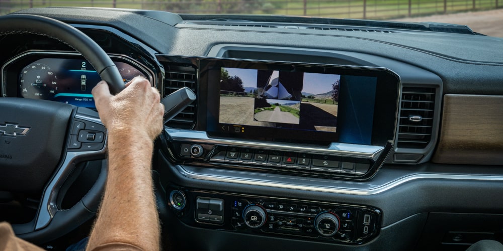 The Interior of a Chevy Silverado HD Featuring a Digital Infotainment Display Showing a Trailer Camera View and Vehicle Controls on the Center Dashboard
