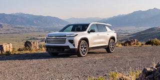 Front Three-Quarter View of a White Chevrolet Traverse High Country Parked on a Scenic Mountain Overlook With Desert Terrain and Mountain Peaks in the Background.