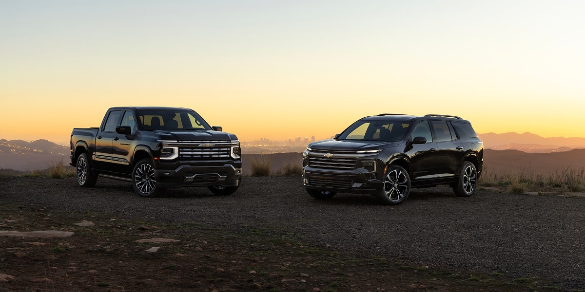 Chevrolet Silverado High Country and Chevrolet Traverse High Country Parked on a Rugged Dirt Landscape at Sunset Beneath a Clear Evening Sky.
