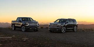 Chevrolet Silverado High Country and Chevrolet Traverse High Country Parked on a Rugged Dirt Landscape at Sunset Beneath a Clear Evening Sky.