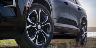 Close-Up of a Chevrolet Traverse High Country Wheel Featuring a Multi-Spoke Alloy Rim Design, All-Season Tire, and Black Exterior Body Panels in an Outdoor Setting.