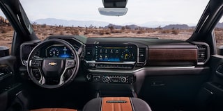 The Interior of a Chevy Silverado LD Featuring a Digital Dashboard, Leather Steering Wheel, and Center Touchscreen Display While Overlooking a Dirt Trail.