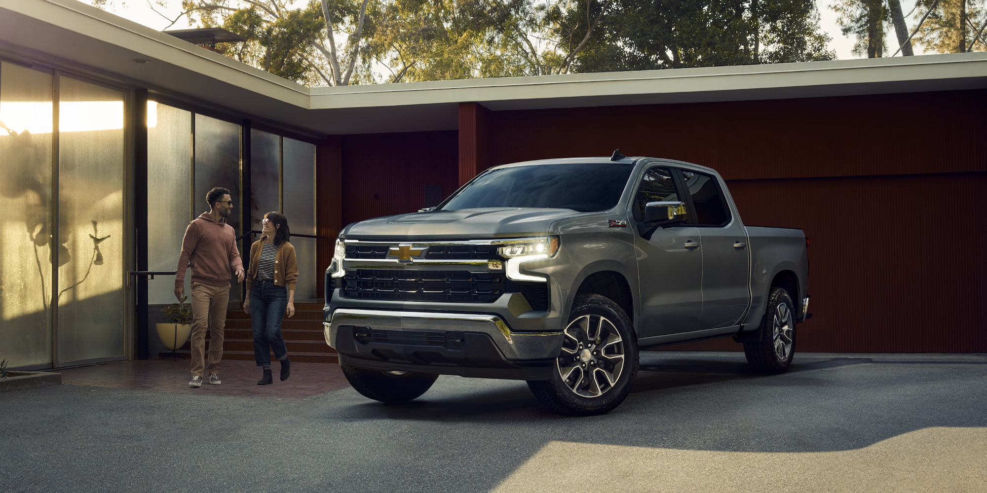 A Couple Walks Toward Their 2025 Chevy Silverado LD Parked in a Driveway