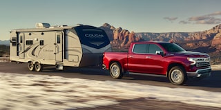 A Red Chevy Silverado 1500 Pickup Truck towing an RV Down a Highway.