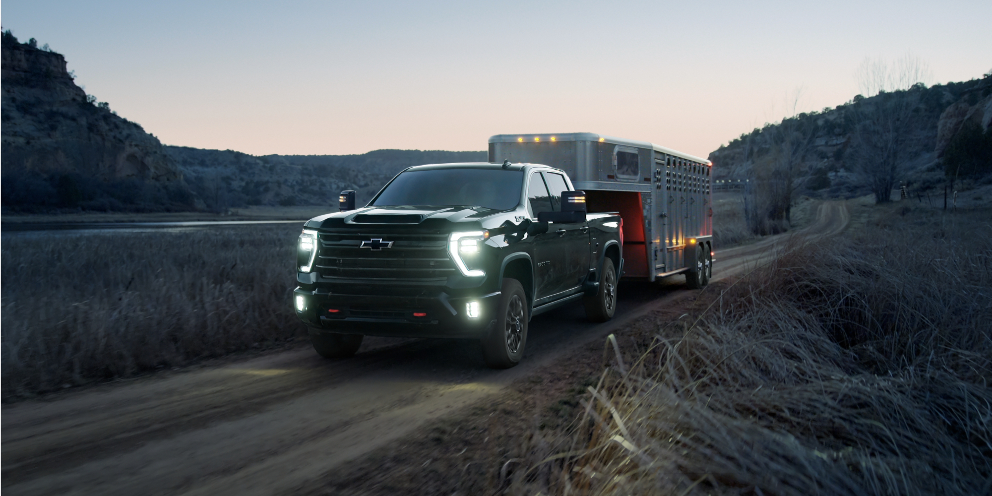 Silverado HD Trail Boss llevando un remolque para animales en una carretera al atardecer