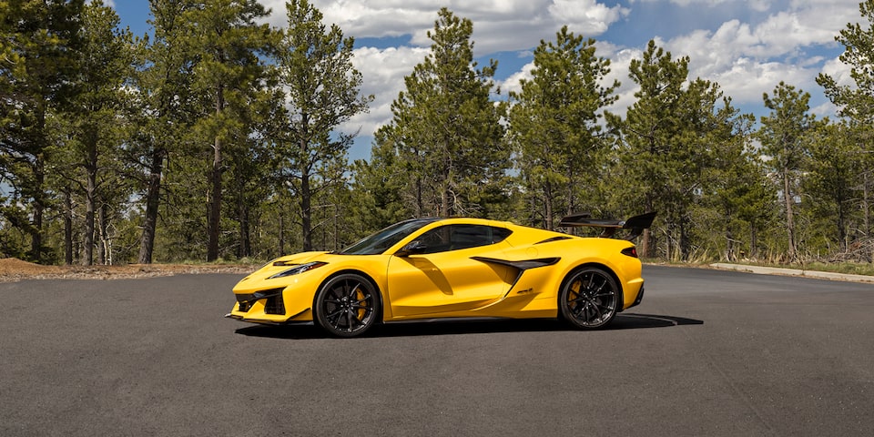 Side View of a Yellow Chevy Corvette ZR1 beside Trees under a Beautiful Blue Sky with Clouds