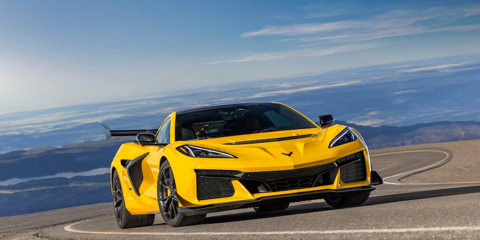Low Angle Three Quarters View of a Yellow Chevy Corvette ZR1 Going down a Road with a Clear Blue Sky