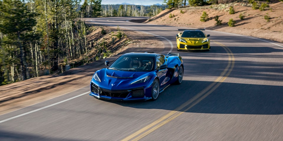Two Blue and Yellow Chevy Corvette ZR1 Racing Down a Road under on a Sunny Day
