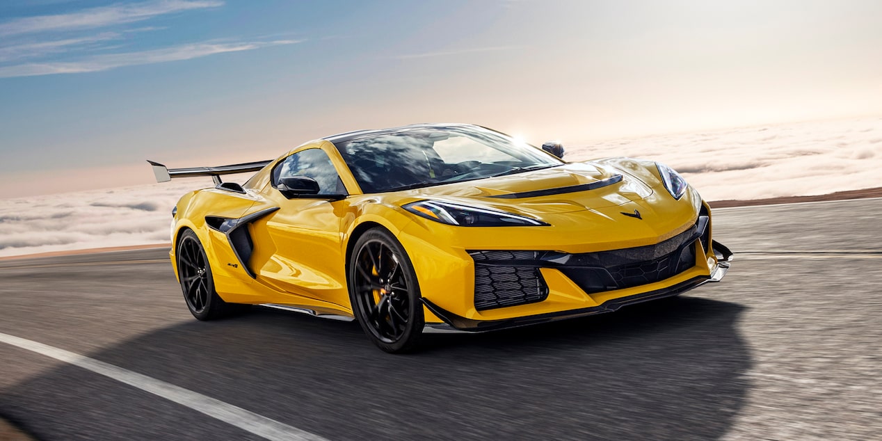 Vista de medio perfil de un Chevy Corvette ZR1 amarillo circulando por un camino, en un día soleado