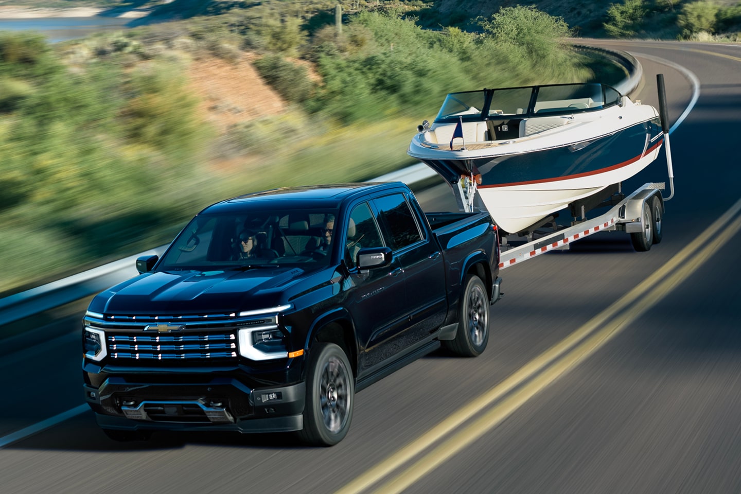 Illustrative: a black Chevrolet Silverado 1500 pickup towing a boat on a two-lane road