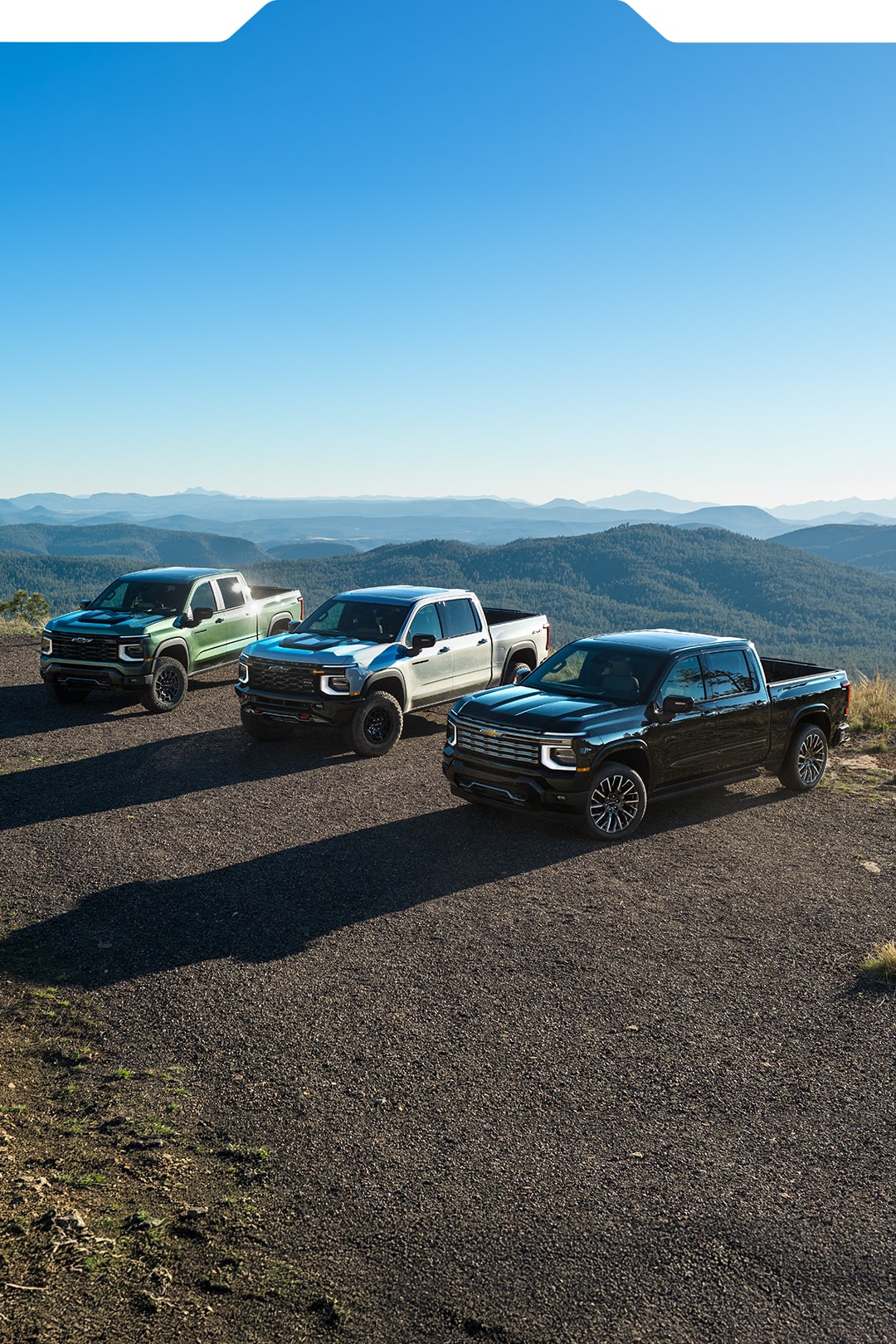 The Sun Shining on Three Chevy Silverado 1500 Trucks Lined Up at the Top of a Mountain with Text Overlay Reading "Trusted. Performance. Legacy."