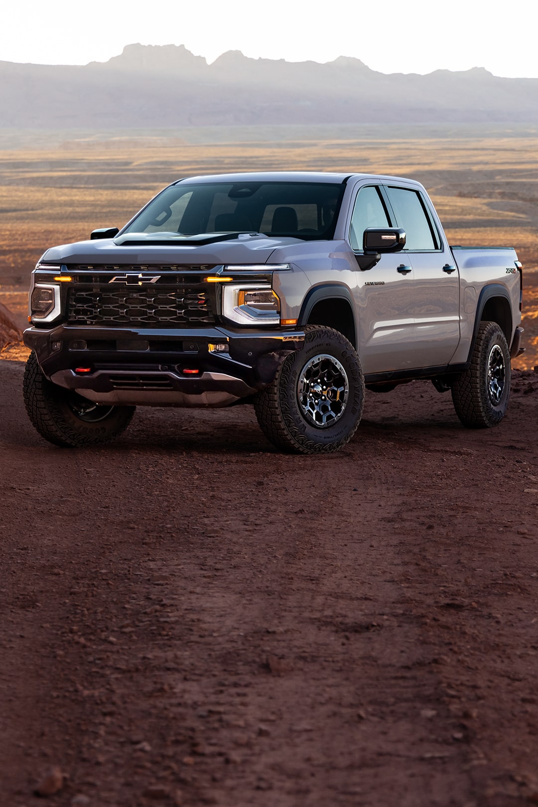 Three-quarters View of a 2027 Chevy Silverado 1500 Parked in an Open Desert with Text Overlay Reading "Rugged and ready for anything."