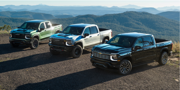 Three Chevy Silverado 1500 Trucks Lined Up at the Top of a Mountain with the Sun Shining Behind Them