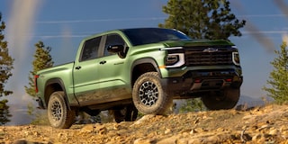 Low Angle Front View of a 2026 Blue Chevy Colorado Going Down a Rocky Road in a Forest
