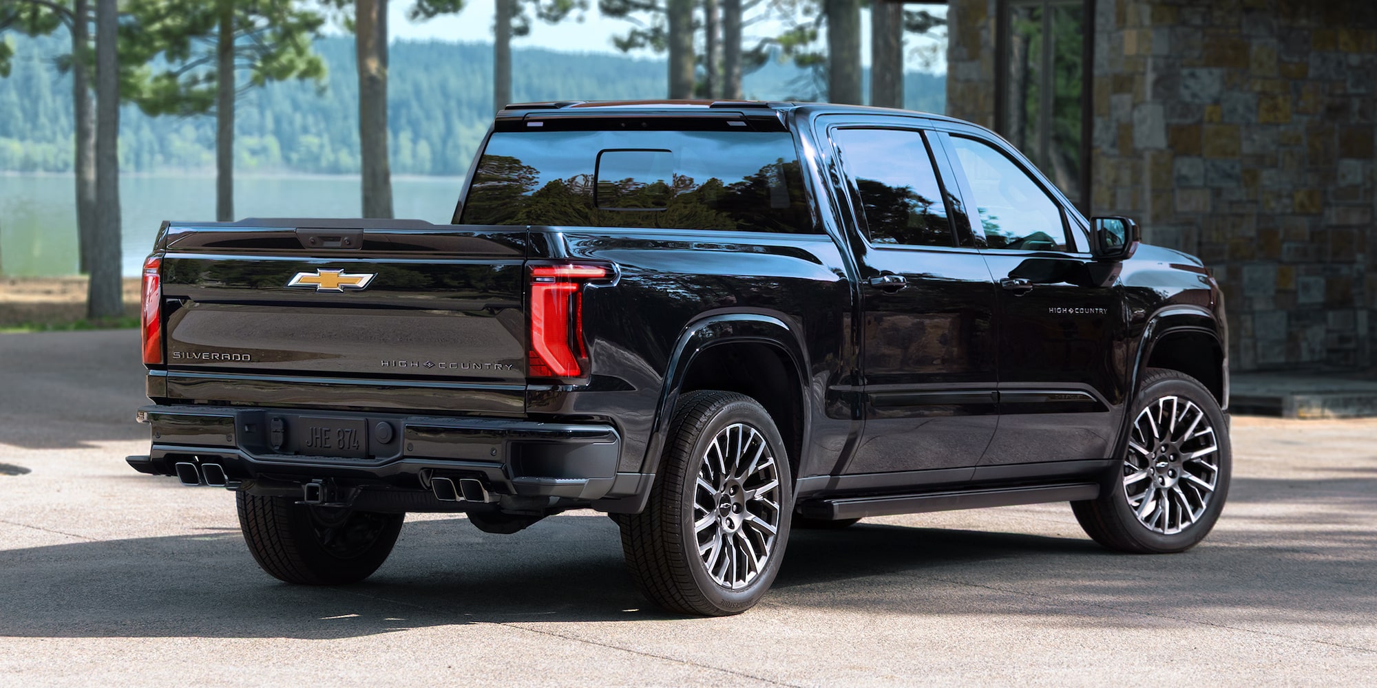 Rear Three-quarters View of a Black 2027 Chevy Silverado 1500 Parked in a Mountain Cabin Driveway