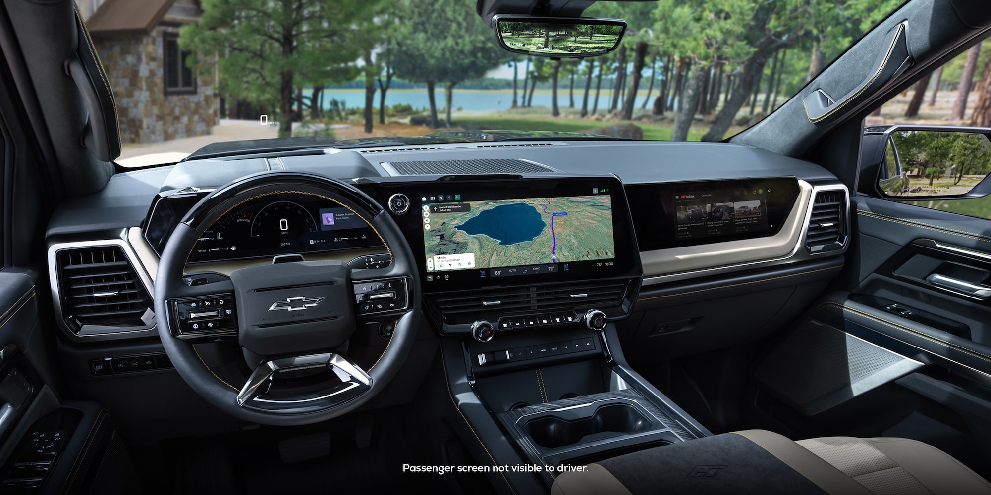 Driver Seat View of the 2027 Chevy Silverado 1500 Front Row Cabin Interior and Dashboard While Outlooking Trees Lining a Lake