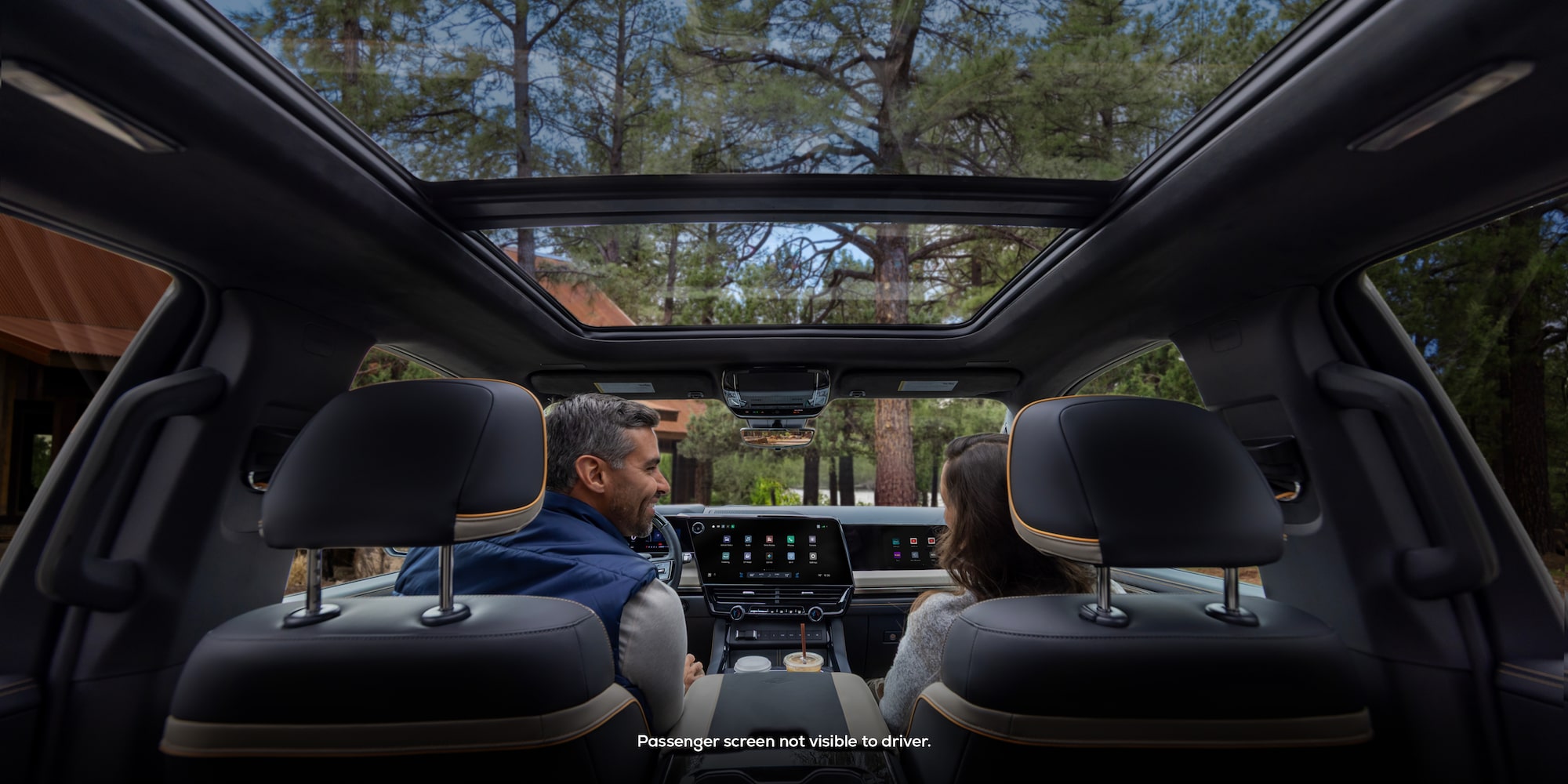 Second Row View of the Sun Roof and a Driver Laughing with a Passenger in a 2027 Chevy Silverado 1500