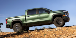 Low Angle Front View of a 2026 Blue Chevy Colorado Going Down a Rocky Road in a Forest