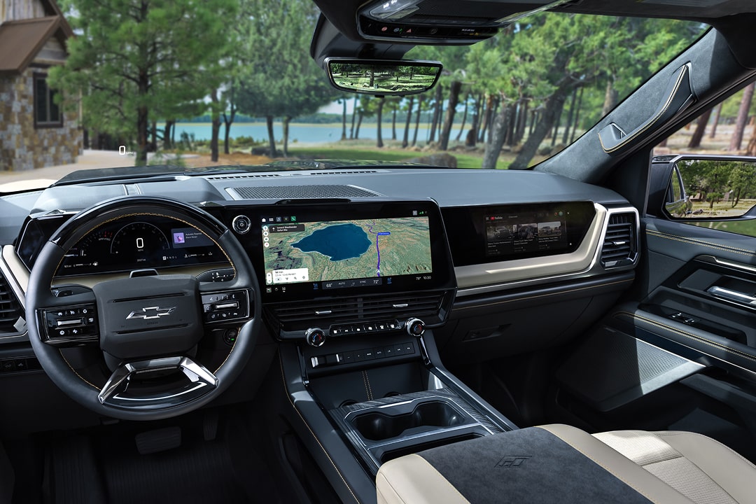 Driver Seat View of the 2027 Chevy Silverado 1500 Front Row Cabin Interior and Dashboard While Outlooking Trees Lining a Lake