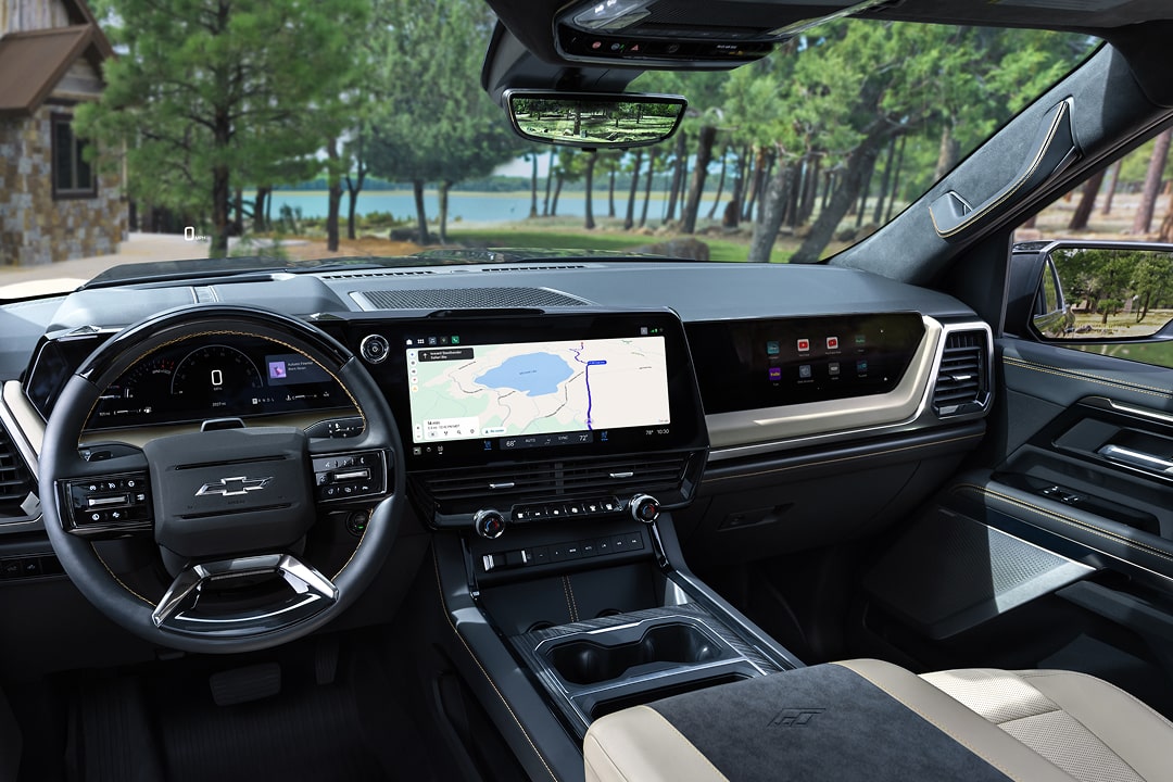 Driver Seat View of the 2027 Chevy Silverado 1500 Front Row Cabin Interior and Dashboard While Outlooking Trees Lining a Lake