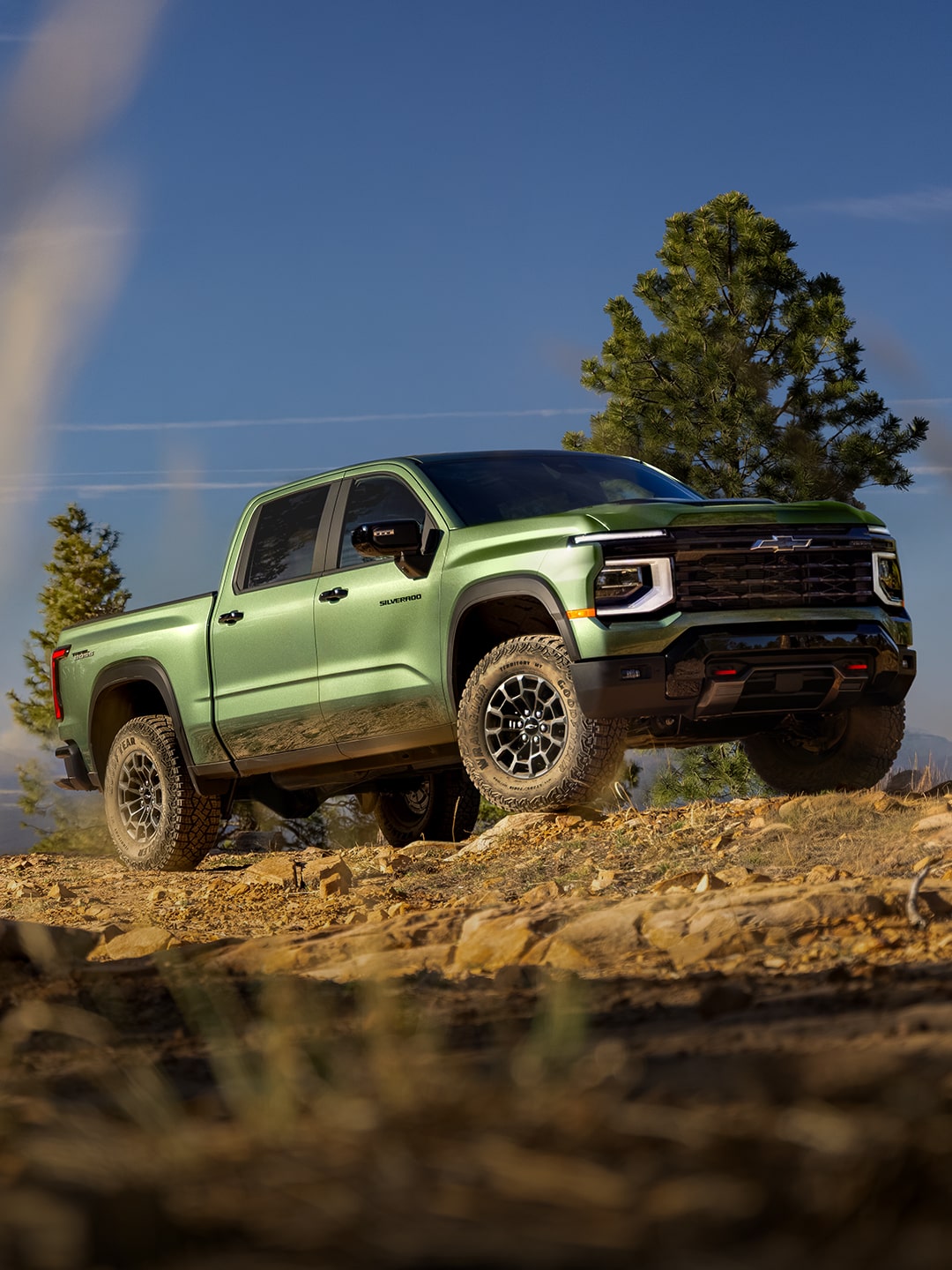 A Green 2027 Chevy Silverado 1500 Off-roading on a Rugged, Rocky Hill with Text Overlay Reading "Next-generation Silverado"