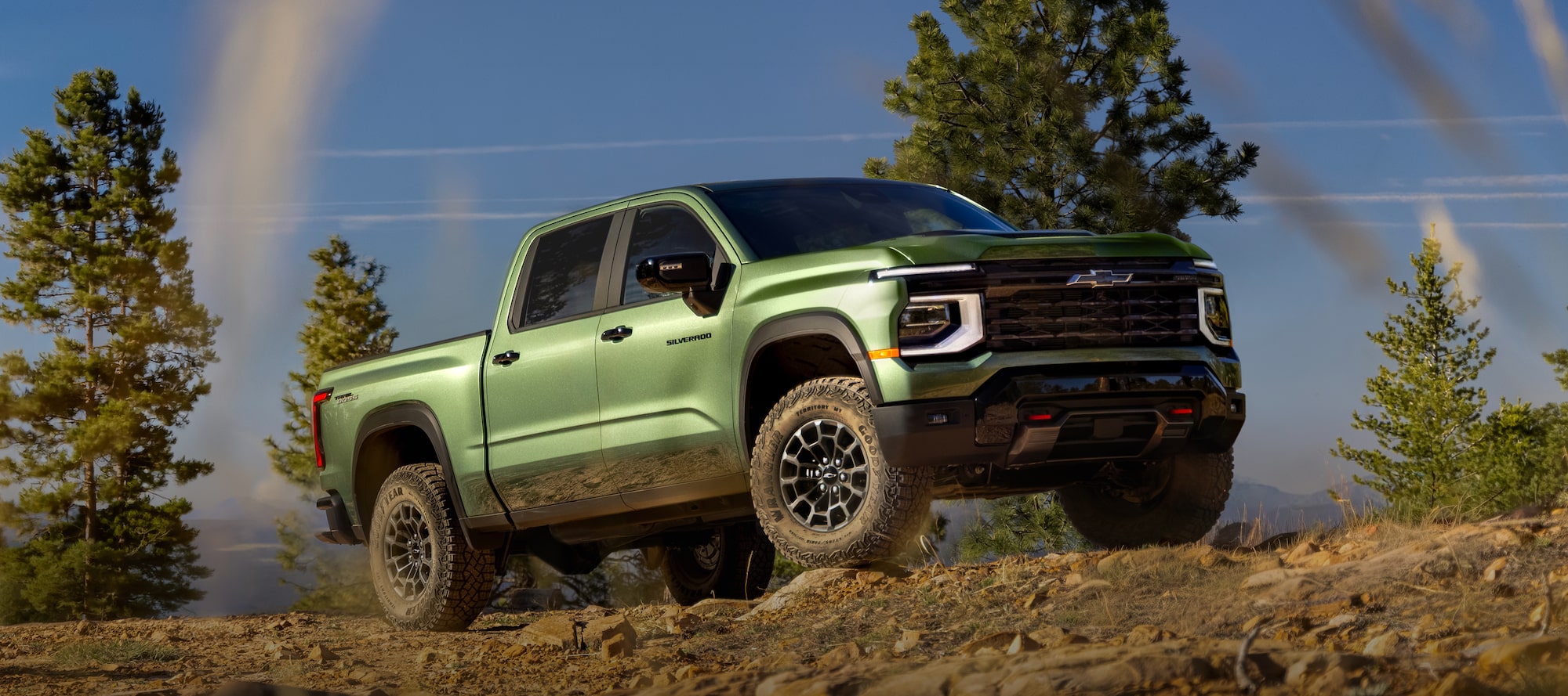 Illustrative: a green Chevrolet Silverado 1500 ZR2 climbing a rocky trail among pine trees