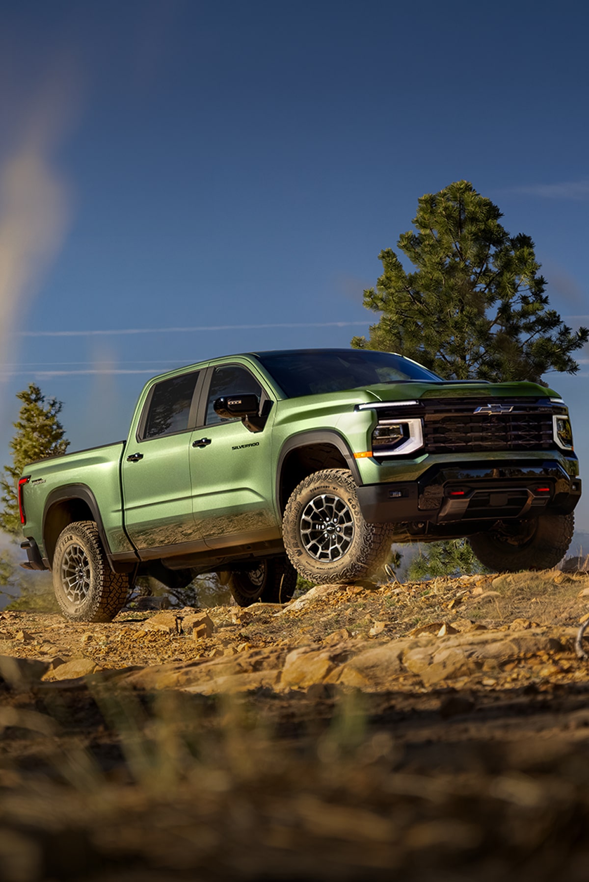 A Green 2027 Chevy Silverado 1500 Off-roading on a Rugged, Rocky Hill with Text Overlay Reading "Next-generation Silverado