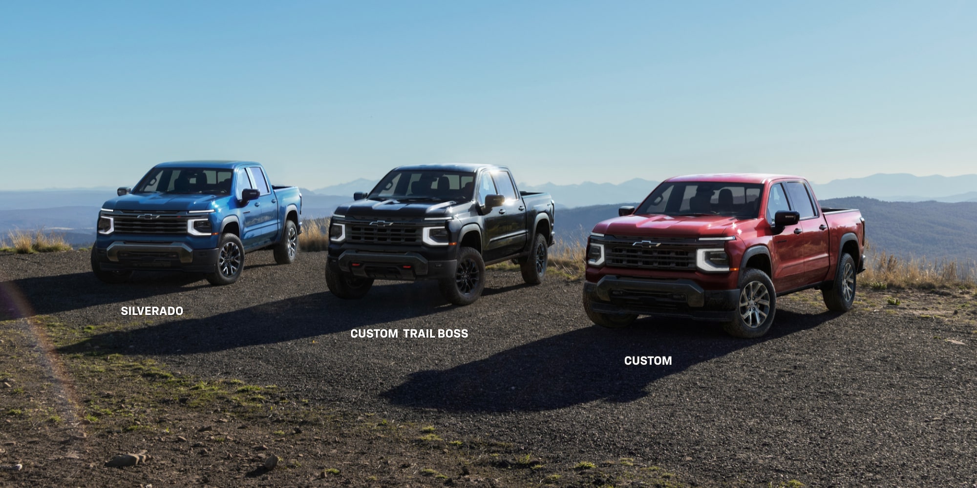 Three 2027 Chevrolet Silverado 1500 trucks on a mountain overlook