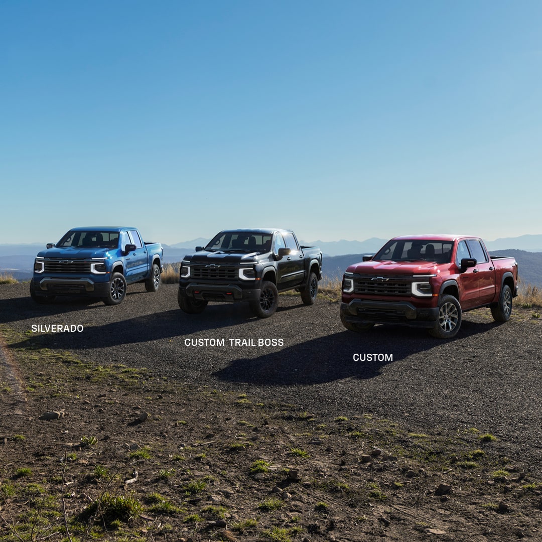 Three Chevy Silverado 1500 Trucks Lined Up at the Top of a Mountain with the Sun Shining Behind Them