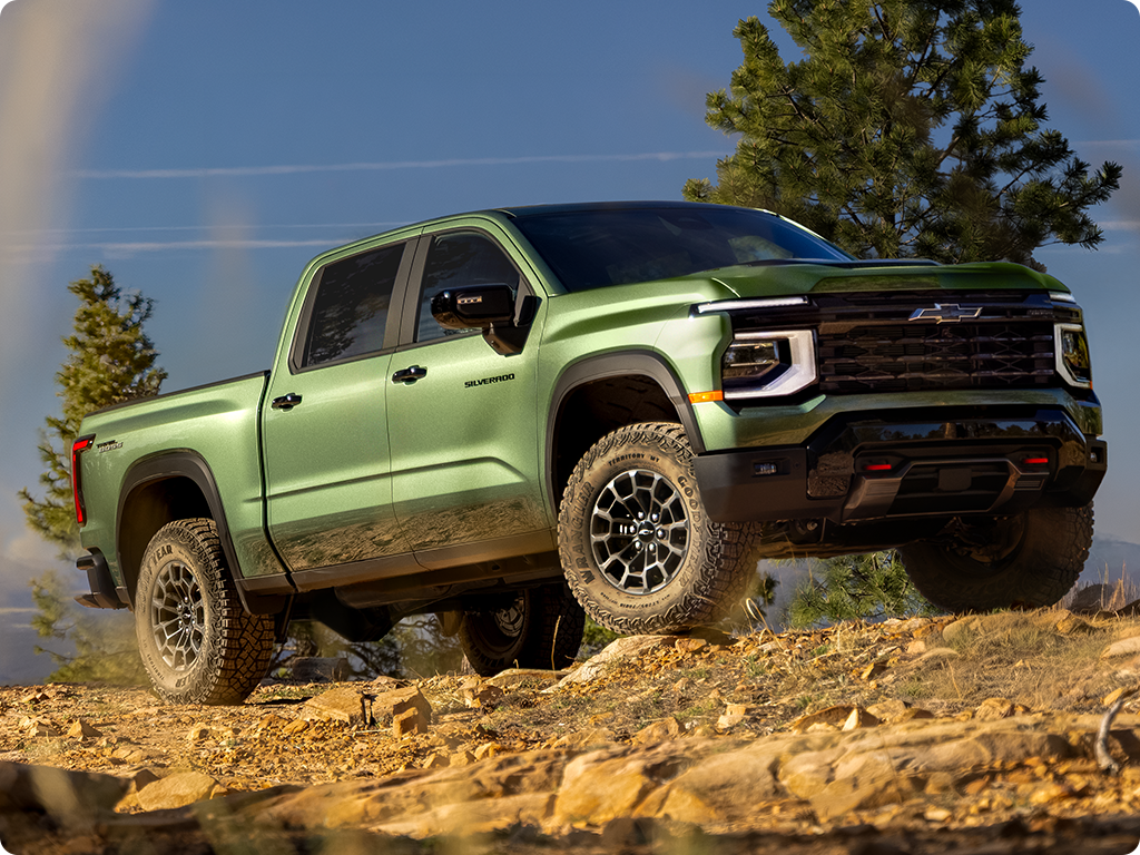 A Green 2027 Chevy Silverado 1500 Off-roading on a Rugged, Rocky Hill with Text Overlay Reading "Trail Boss"