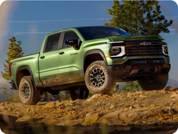 A Green 2027 Chevy Silverado 1500 Off-roading on a Rugged, Rocky Hill with Text Overlay Reading "Trail Boss"