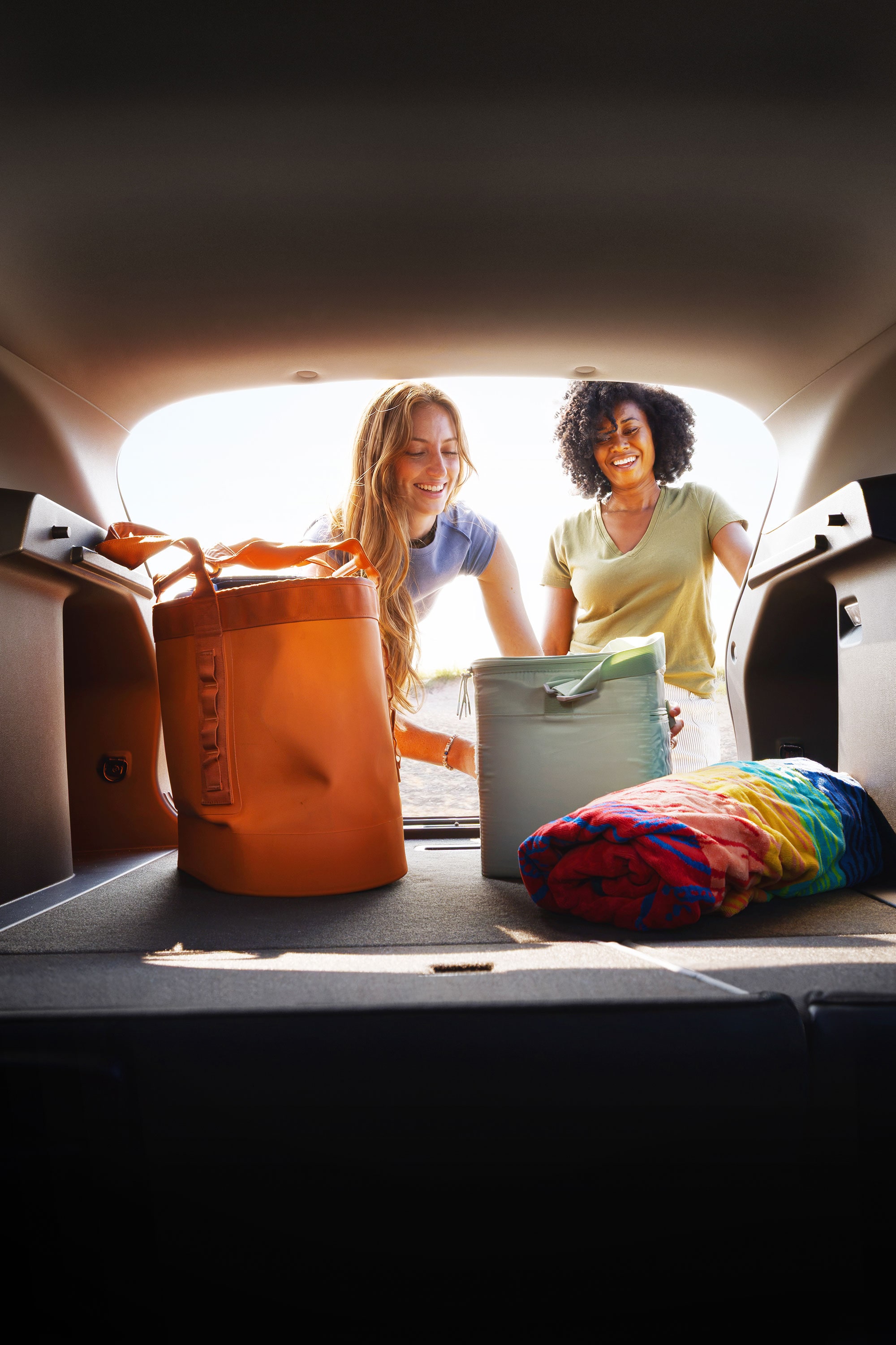 A View From the Chevy Trax Cargo Area Looking Toward Two People Standing Behind the Open Liftgate With Travel Bags and Luggage Inside the Vehicle.