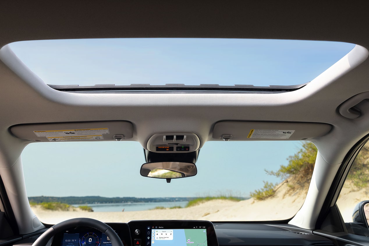 A View of the Chevy Trax Interior Looking Through the Open Sunroof With Blue Sky Visible Above the Front Cabin.