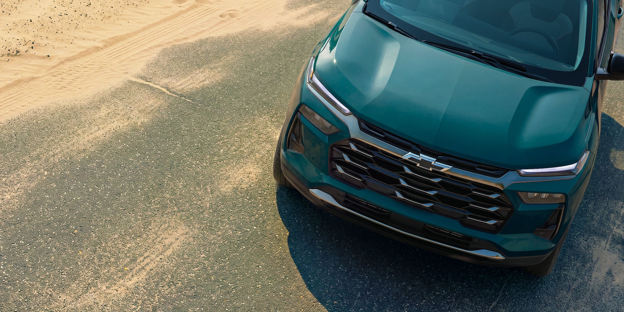 An Elevated Front Three-Quarter View of a Chevy Trax Parked Beside a Sandy Beach Road.