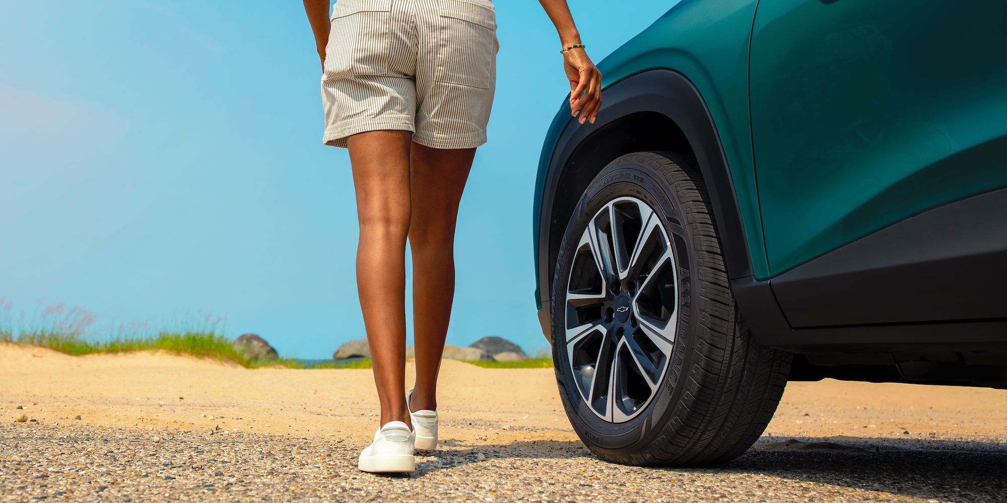 A Close-Up of a Person Walking Beside a Chevy Trax Showing the Rear Wheel and Lower Body Styling.