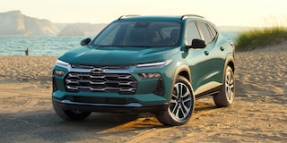 A Chevy Trax ACTIV Parked on a Beach With Ocean Views and Coastal Cliffs in the Distance.