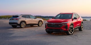A Red Chevy Trax RS and a Silver Chevy Trax ACTIV Parked Side by Side on a Coastal Road at Sunset.
