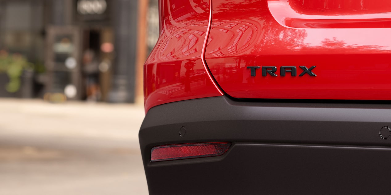 A Close-Up View of the Black TRAX Badge on the Rear of a Red Chevy Trax.