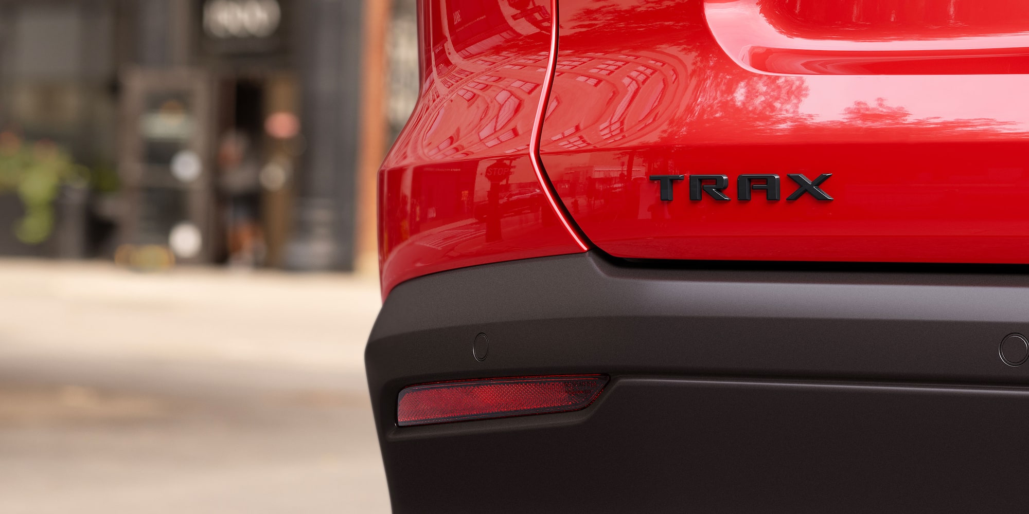 A Close-Up View of the Black TRAX Badge on the Rear of a Red Chevy Trax.