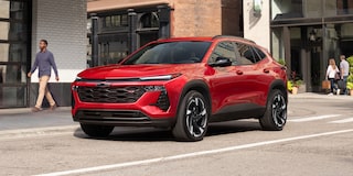 A Red Chevy Trax Parked Along a City Street in Front of Modern Buildings.